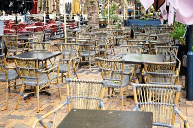 Avrupalı bir turist kasabasında boş kafeterya metal sandalyeler ve masalar. Güneşli yaz sabahı, geniş açı, insan yok.