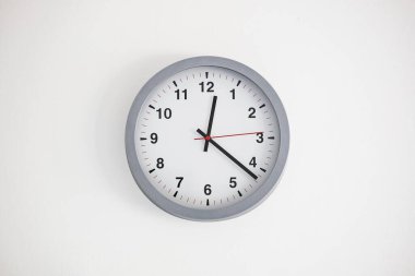 Modern, analog, white face large clock hanging on a white wall. Interior close up shot, no people