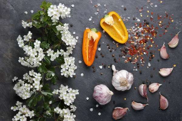 Early summer white  flower blossoms with pink garlic and Himalayan rock salt with colorful pepper and chilli on slate