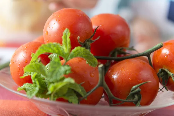 Detail of a glass plate with tomatoes and peppermint.