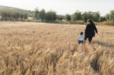 Bir kadın ve bir çocuk günbatımında bir histaminin alanda yürüyüş.
