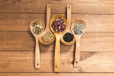 Tahta kaşık ile infüzyon, ahşap arka plan üzerinde rustik tarzı için farklı otlar.