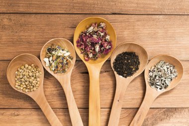 Tahta kaşık ile infüzyon, ahşap arka plan üzerinde rustik tarzı için farklı otlar.