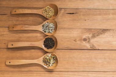 Tahta kaşık ile infüzyon, ahşap arka plan üzerinde rustik tarzı için farklı otlar.