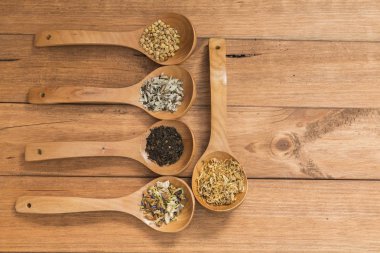 Tahta kaşık ile infüzyon, ahşap arka plan üzerinde rustik tarzı için farklı otlar.