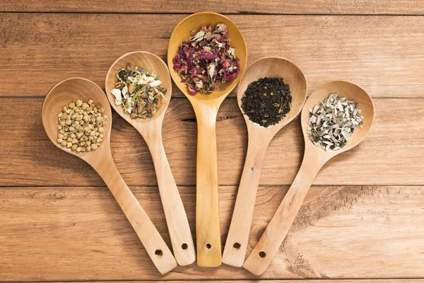 Tahta kaşık ile infüzyon, ahşap arka plan üzerinde rustik tarzı için farklı otlar.