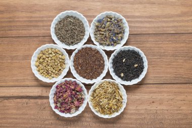 İnfüzyon, ahşap arka plan üzerinde rustik tarzı için farklı otlar ile beyaz kase.