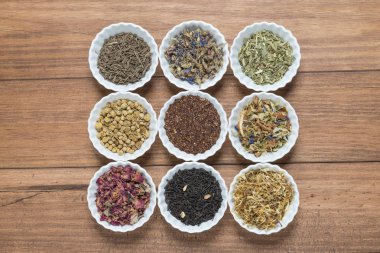 İnfüzyon, ahşap arka plan üzerinde rustik tarzı için farklı otlar ile beyaz kase.