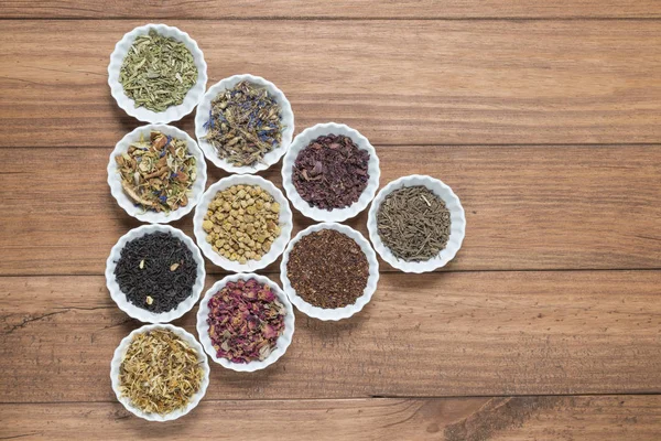 İnfüzyon, ahşap arka plan üzerinde rustik tarzı için farklı otlar ile beyaz kase.