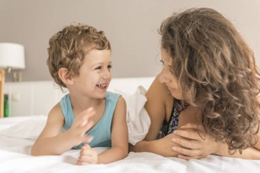 Bir kadın ve oğlu yatakta oynama ve el hareketi.