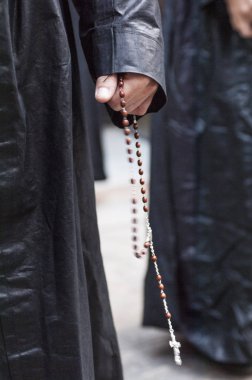 Detail of the hand of a penitent with a rosary, counting the beads while praying. clipart