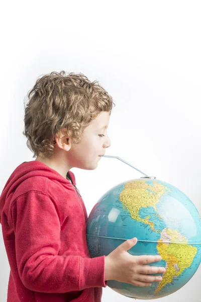 Child holding a globe in his arms and drinking from it with a st — Stock Photo, Image
