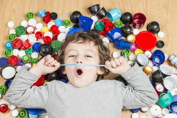 Plastik tıpalar ile çevrili yerde yatan çocuk.