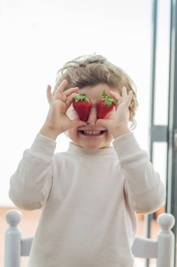 İki çilekle gözlerini kapatan çocuk