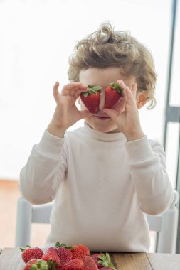İki çilekle gözlerini kapatan çocuk
