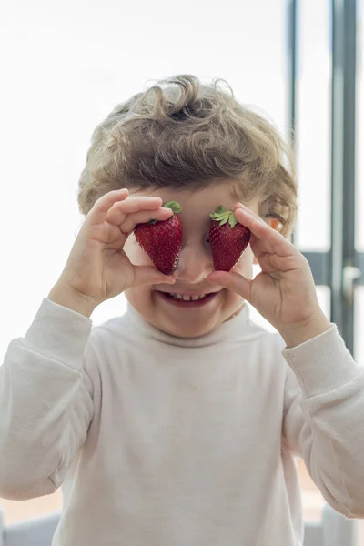 Child covering his eyes with two strawberries — Stock Photo, Image
