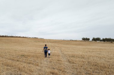 Bir kadın ve bir çocuk biçilmiş buğday tarlasında yürüyorlar..