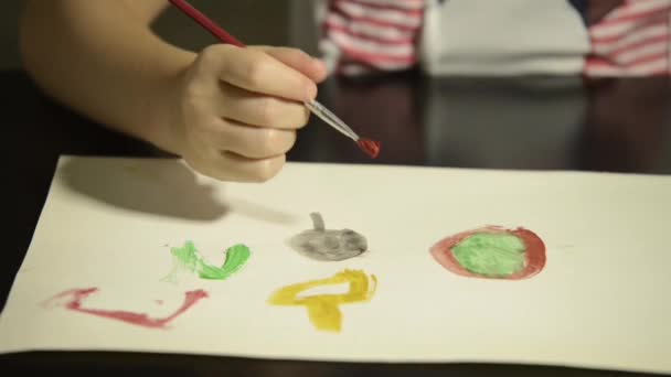 紙に水彩画を描いたブラシで子供の手をクローズアップ 学校と子供の頃の概念に戻る — ストック動画