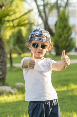 Kapak lı ve güneş gözlüğü takan bir çocuğun portresi.