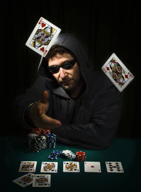 Bir masada kartlarını gösteren poker oynayan adam.