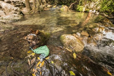 Temiz su akıntısının kıyısındaki terk edilmiş çöpler..