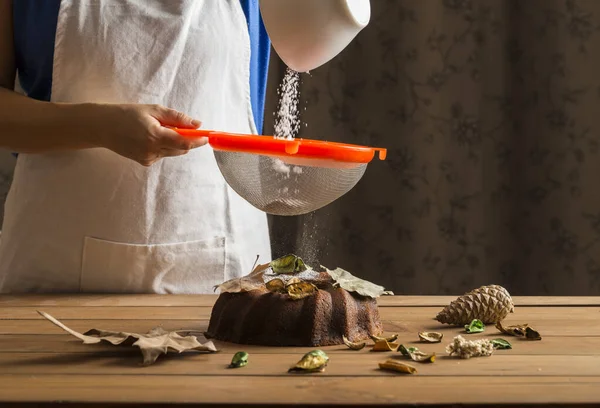 Mujer rociando con azúcar glaseado una torta de esponja . — Foto de Stock