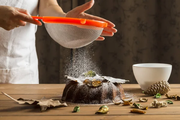 Mujer rociando con azúcar glaseado una torta de esponja . — Foto de Stock