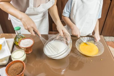 Bir kadın ve bir çocuk yumurta çırpıyor..