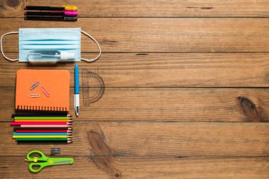 Çeşitli okul malzemeleri, yüz maskesi ve tahta tahtalarda hidroseksüel jel. Covid19 salgınından sonra okul konseptine dönelim..