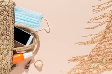 Plaj eşyalarının üst görüntüsü, yüz maskesi ve pembe arka planda hidro alkolik jeli. Covid19 Coronavirus salgını sırasında yaz ve tatil konsepti.