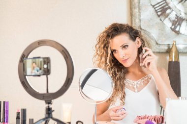 Genç bayan vlogger video bloğu için bir makyaj videosu kaydediyor. Sosyal medya kavramında pazarlama üzerinde etkili.