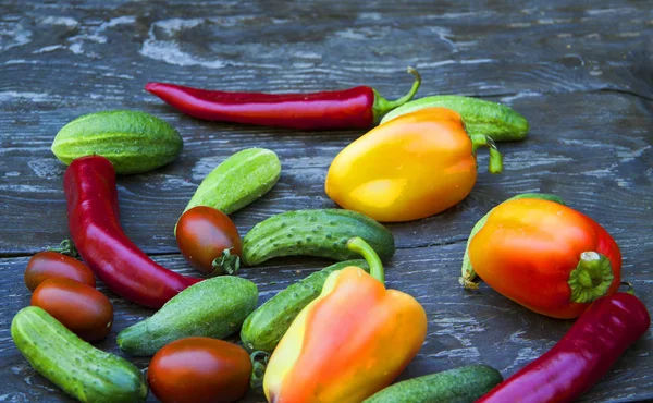 Komkommers, tomaten, paprika's, op een houten tafel — Stockfoto