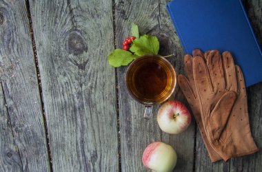 Sonbahar ahşap arka plan dinlenme fincan çay, elma ve eldiven ile okuma, parkta yürümek