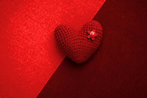 red knitted heart on a red background, a symbol of love to congratulate the holiday