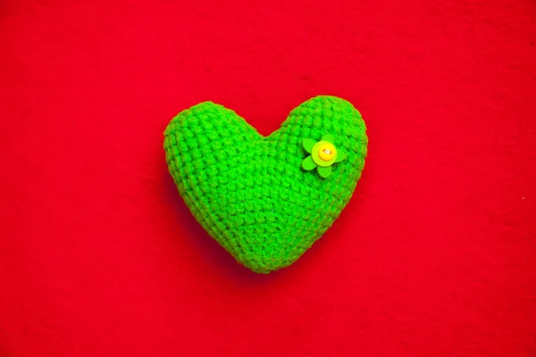Corazón de punto verde sobre un fondo rojo, un símbolo de amor para felicitar a la fiesta — Foto de Stock