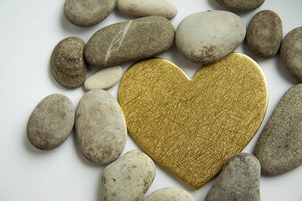 Corazón dorado y piedras sobre un fondo blanco — Foto de Stock