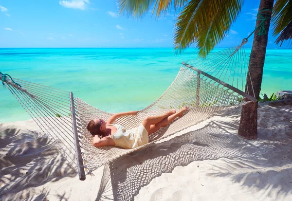 Vrouw is ontspannen in een hangmat op het strand tussen de Palm. — Stockfoto