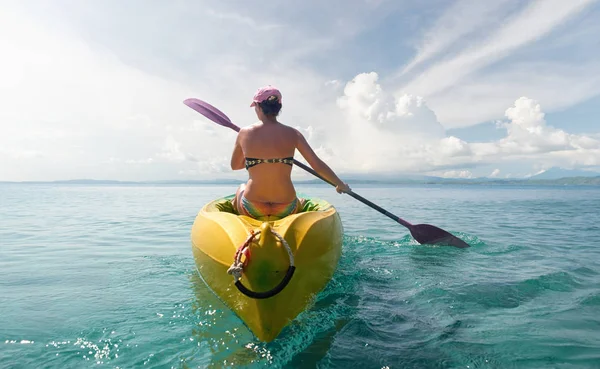 Путешествующая женщина исследует спокойный тропический залив на каяке — стоковое фото