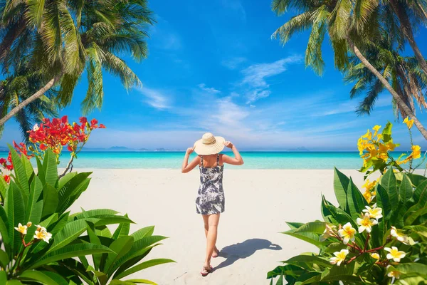 Young woman resting during summer vacation on paradise beach and surrounded by tropical flowers and palm trees. — Stock Photo, Image