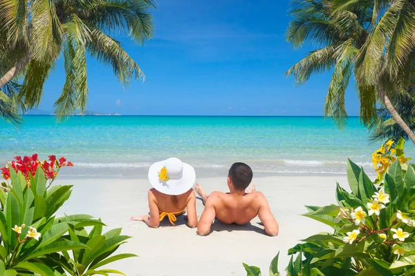 Happy couple resting on a tropical beach on a sunny summer day — Stock Photo, Image