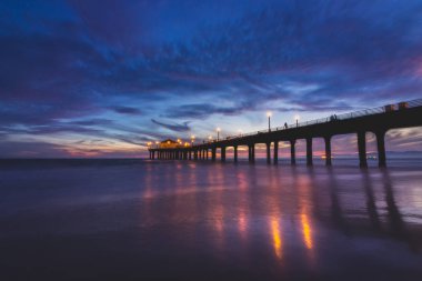 Renkli gökyüzü ve bulutlar üzerinde Manhattan Beach iskelesinden yumuşak dalgalar sahile, Manhattan Beach, Kaliforniya yıkama ile güneş battıktan sonra uzun pozlama atış