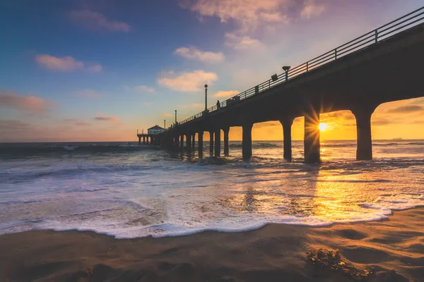Renkli gökyüzü ve bulutlar üzerinde Manhattan Beach iskelesinden yumuşak dalgalar sahile, Manhattan Beach, Kaliforniya yıkama ile gün batımında