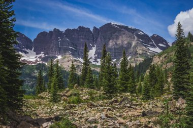 Güneşli bir günde, Colorado, Aspen yakınlarında mavi gökyüzü ile engebeli Krater Gölü patikasından görülen görkemli Maroon Bells tepeleri.