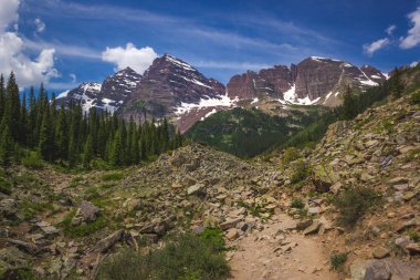 Güneşli bir günde, Colorado, Aspen yakınlarında mavi gökyüzü ile engebeli Krater Gölü patikasından görülen görkemli Maroon Bells tepeleri.