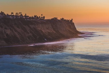 Uzun pozlama kıyı Palos Verdes Estates güneş siluet dik kayalıklarla, ağaçlar ve evleri yanı sıra düz okyanus dalgaları, Palos Verdes Estates, California ile battıktan sonra alınan vurdu