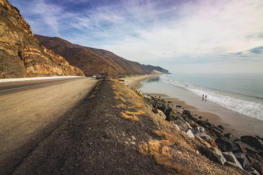 Iconic View of Pacific Coast Highway winding along the Southern California coast with the Santa Monica Mountains on one side of the road and Pacific Ocean on the other clipart