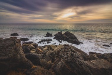 Kaya oluşumları plajda, Malibu, Kaliforniya içine çökmesini dalgaları ile nokta Dume devlet plaj boyunca batımında dramatik gökyüzü