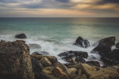 Kaya oluşumları plajda, Malibu, Kaliforniya içine çökmesini dalgaları ile nokta Dume devlet plaj boyunca batımında dramatik gökyüzü