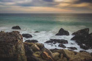 Kaya oluşumları plajda, Malibu, Kaliforniya içine çökmesini dalgaları ile nokta Dume devlet plaj boyunca batımında dramatik gökyüzü