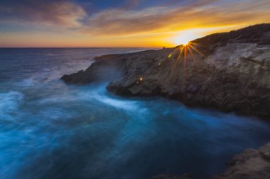 Stunning long-exposure view of smooth waves crashing into rock formations at sunset, Sequit Point, Leo Carrillo State Beach, Malibu, California clipart